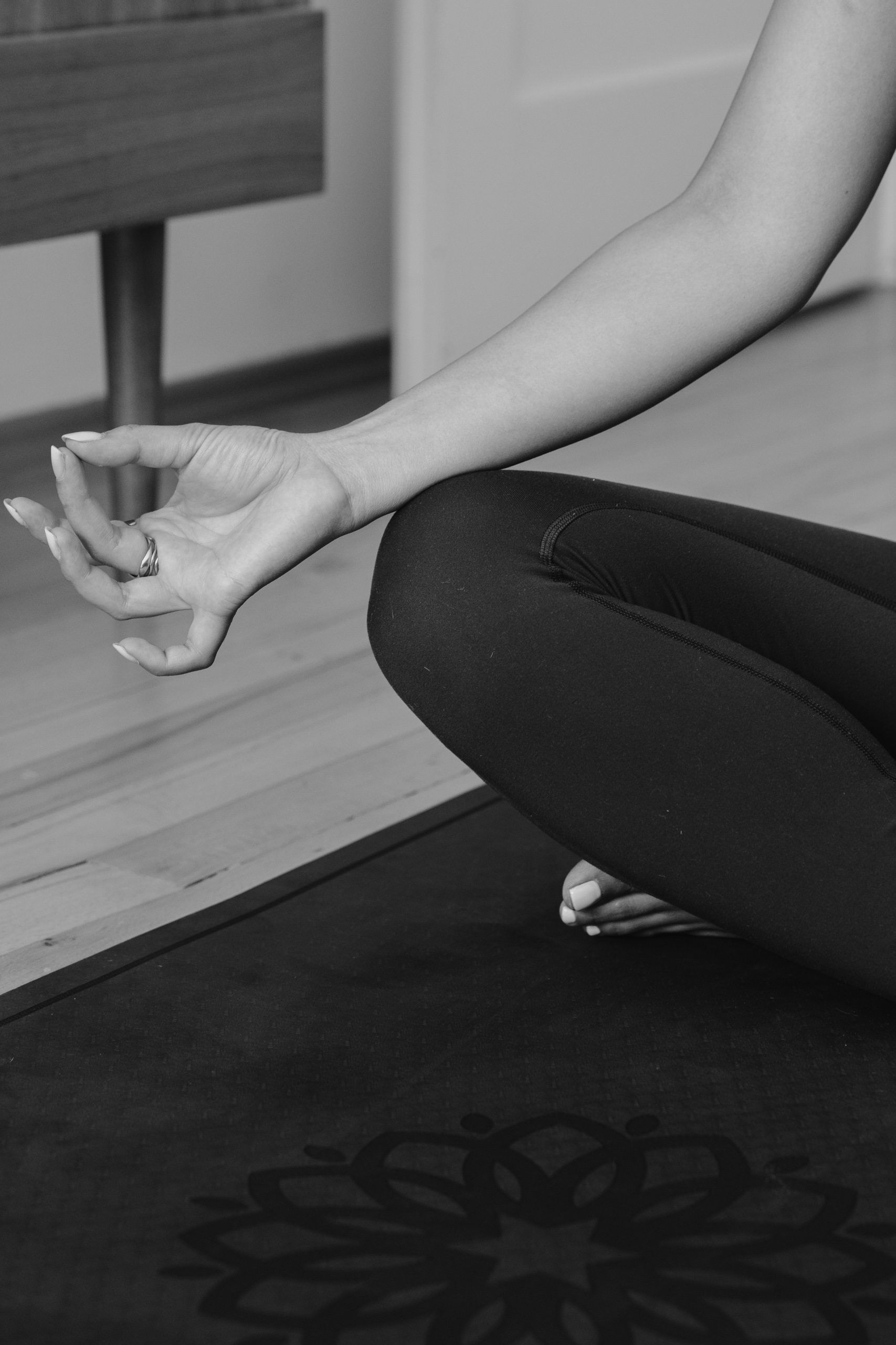 A woman in a meditation hand gesture on a yoga mat, wearing tacet